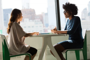 Two ladies sitting at a desk having a meeting 